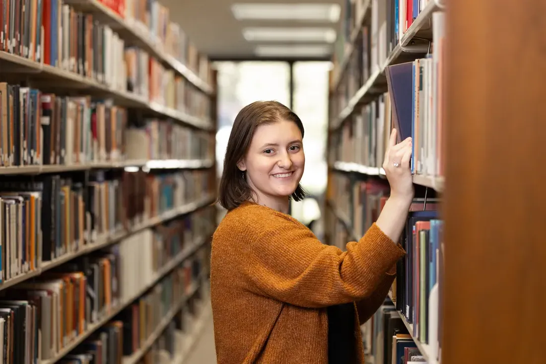 A student taking books off the shelf in the library.